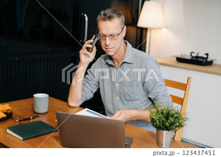 Mature male talk mobile phones and working on laptop computers, online business, work from home, teleworking concept. 123437451