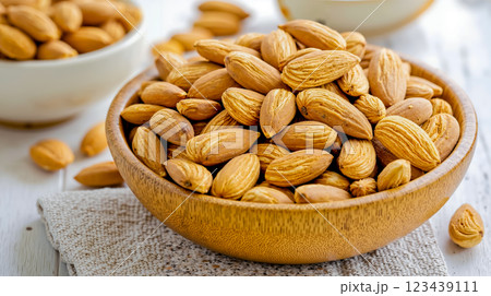 A wooden bowl filled with almonds sitting on top of a table 123439111