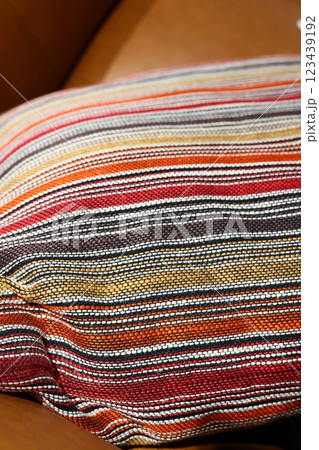 A Beautiful and Colorful Striped Pillow Resting Comfortably on a Cozy Leather Sofa 123439192