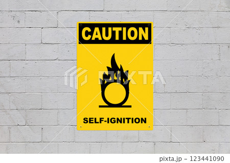 Caution, Self ignition - Sign on a cinder block wall 123441090