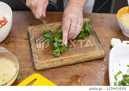 Hands chop green onions on a cutting board. Prepare vegetable salad. Hands chop green onions on a cutting board. Prepare vegetable salad. 123441639
