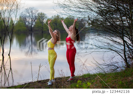 Two adult women in bright tracksuits are playing sports outdoors. Two adult women in bright tracksuits are playing sports outdoors. 123442116
