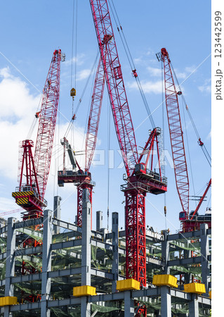 Low-angle view of cranes and steel structures of building construction with a blue sky background in Taiwan. Low-angle view of cranes and steel structures of building construction with a blue sky background in Taiwan. 123442599