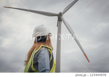 An engineer keenly observing the ongoing wind turbine installation process at a renewable energy site, ensuring all aspects align with development goals and efficiency standards for the future 123444976