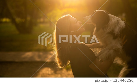Young Caucasian woman hugging her border collie dog while walking in the park.  123446256