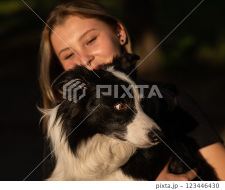 Young Caucasian woman hugging her border collie dog while walking in the park.  123446430