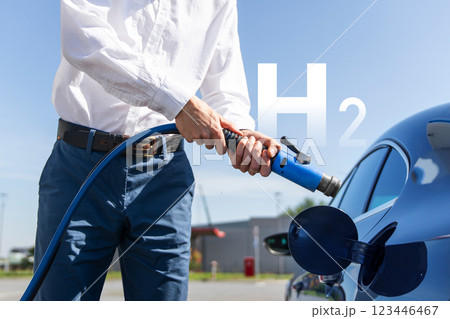 Man holds a hydrogen fueling nozzle on a hydrogen filling station. Refueling car with hydrogen fuel. Man holds a hydrogen fueling nozzle on a hydrogen filling station. Refueling car with hydrogen fuel. 123446467
