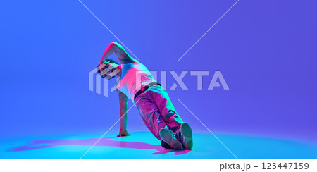 Talented and energetic young man,dancer in motion, performing breakdance against gradient blue purple background in neon light Talented and energetic young man,dancer in motion, performing breakdance against gradient blue purple background in neon light 123447159