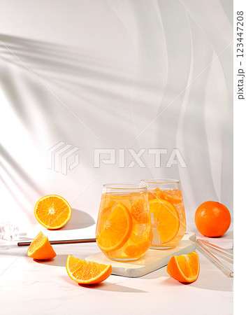 Orange juice and oranges on elegant kitchen table with long hard shadows. Modern still life with citrus fruits, minimal detox diet concept, summer vitamin drinks, selective focus 123447208