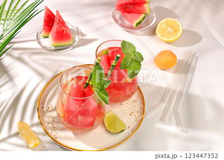 Ice cold homemade lemonade or cocktail with mint, watermelon and fruit, a recipe for a refreshing summer drink. Two glasses with fruit drink on sunny table, detox diet and weight loss concept, menu Ice cold homemade lemonade or cocktail with mint, watermelon and fruit, a recipe for a refreshing summer drink. Two glasses with fruit drink on sunny table, detox diet and weight loss concept, menu 123447352
