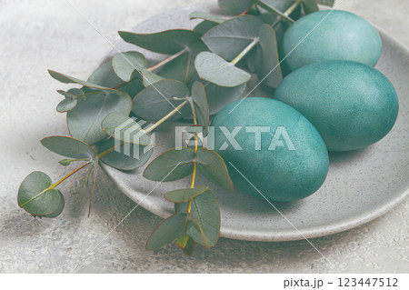 Easter colored eggs, in turquoise tones, on a gray plate, with a branch of eucalyptus, Easter card, top view, no people Easter colored eggs, in turquoise tones, on a gray plate, with a branch of eucalyptus, Easter card, top view, no people 123447512