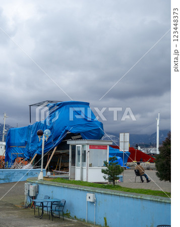 Ship on the shore. Winter season. The ship was covered with a tarpaulin. Ship repair concept. The yacht is not afloat Ship on the shore. Winter season. The ship was covered with a tarpaulin. Ship repair concept. The yacht is not afloat 123448373