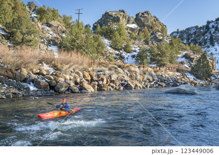 senior kayaker in a whitewater kayak paddling upstream of Arkansas River above Hecla Junction, Colorado in winter scenery 123449006