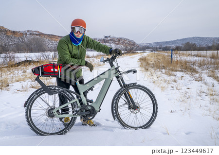 senior male cyclist with a touring electric bike in Colorado foothills in winter scenery senior male cyclist with a touring electric bike in Colorado foothills in winter scenery 123449617