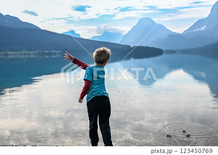 Young boy skipping rocks on the shore of Bow Lake in western Alberta, Canada in Banff National Park 123450769