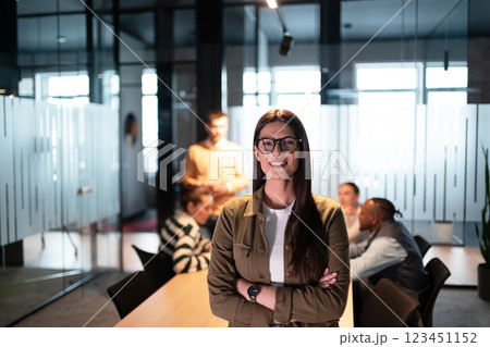 Businesswoman standing confidently in a modern office meeting room. Diverse team on a business meeting in a startup coworking open space office environment collaborating in the background. Corporate Businesswoman standing confidently in a modern office meeting room. Diverse team on a business meeting in a startup coworking open space office environment collaborating in the background. Corporate 123451152