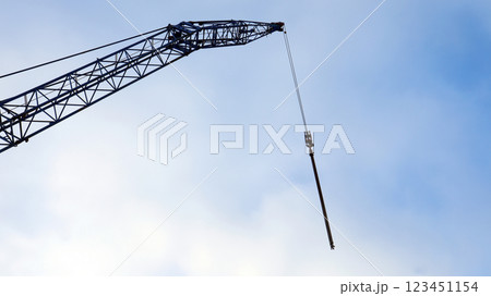 Crane boom suspended against a bright blue sky with a chain hanging down Crane boom suspended against a bright blue sky with a chain hanging down 123451154