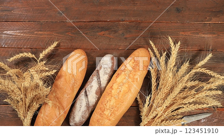 Freshly baked homemade bread, french sourdough baguette with crispy crust and ears of rye and wheat on wooden background with place for text, modern bakery concept, healthy natural food, selective 123451910