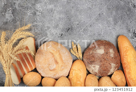 Assortment of homemade sourdough bread with crispy crust and ears of rye and wheat on gray concrete background with place for text, modern bakery concept, top view, healthy natural food, selective Assortment of homemade sourdough bread with crispy crust and ears of rye and wheat on gray concrete background with place for text, modern bakery concept, top view, healthy natural food, selective 123451912