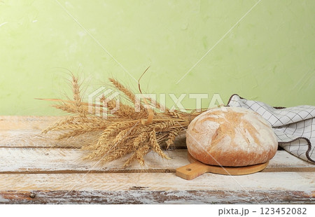 Freshly baked homemade sourdough bread with crispy crust and ears of rye and wheat on an old concrete background with place for text, modern bakery concept, healthy natural food, selective focus 123452082