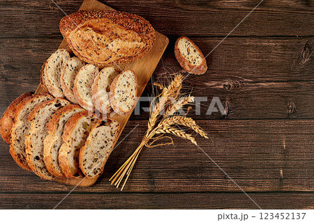 Freshly baked whole grain homemade sourdough bread with crispy crust, sliced and ears of wheat on wooden table, modern baking concept, healthy natural food 123452137