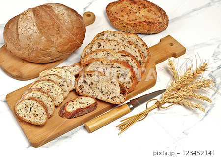 Freshly baked whole grain homemade sourdough bread with crispy crust, sliced and ears of wheat on marble background, modern baking concept, healthy natural food Freshly baked whole grain homemade sourdough bread with crispy crust, sliced and ears of wheat on marble background, modern baking concept, healthy natural food 123452141