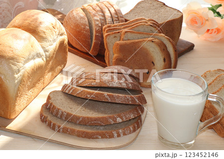A loaf, slices of fresh bread and a cup of milk on a sunny table. Healthy food A loaf, slices of fresh bread and a cup of milk on a sunny table. Healthy food 123452146