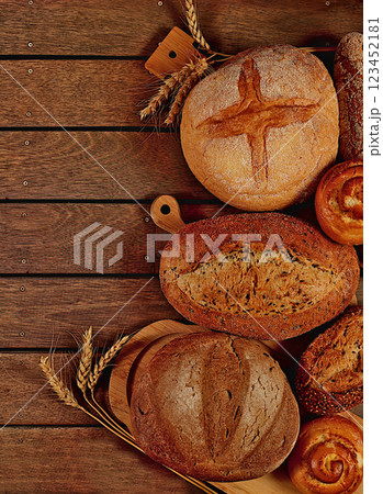 Freshly baked bakery products, whole grain homemade bread, different types of round sourdough bread with crispy crust, baguettes, buns and ears of wheat on wooden background, modern baking concept, 123452181