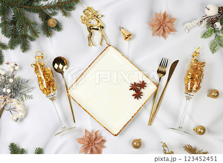 Christmas table setting. Festive New Year's cutlery with a napkin on a plate on a marble concrete background, festive composition with fir branches and a glass of champagne, kitchen background. 123452451