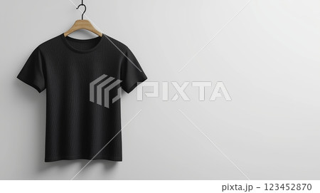 Simple black t-shirt displayed on a wooden hanger against a white wall 123452870