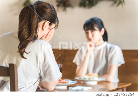 カフェでランチをしながら悩み相談を友達にする若いアジア人女性 カフェでランチをしながら悩み相談を友達にする若いアジア人女性 123455254