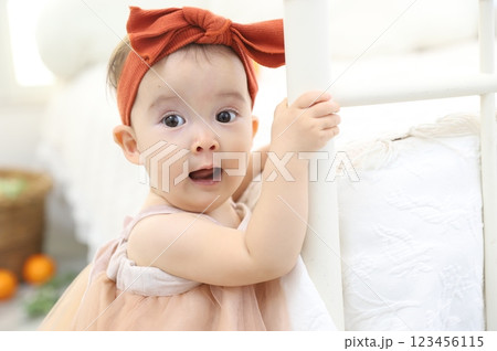 つかまり立ちでビックリした表情の赤ちゃん つかまり立ちでビックリした表情の赤ちゃん 123456115