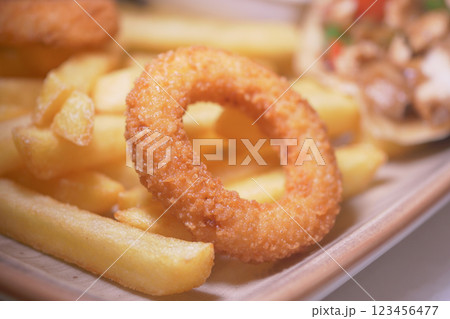 Crispy onion rings and golden fries served on a wooden plate 123456477