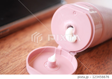 Squeezing moisturizing cream from a pink tube on wooden surface Squeezing moisturizing cream from a pink tube on wooden surface 123456676