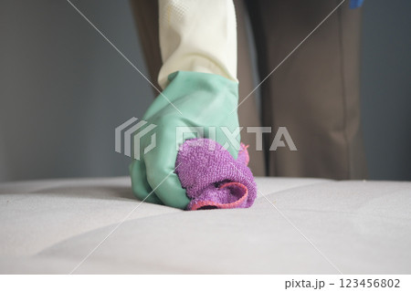 Cleaning a mattress with a cloth and rubber gloves in a bedroom 123456802