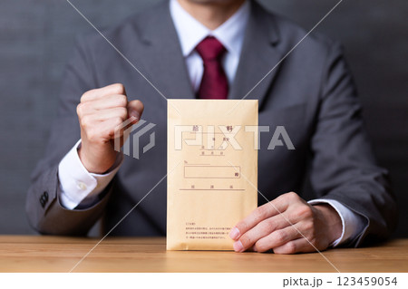 グレーのスーツを着て給料袋を持ってガッツポーズをするミドル男性ビジネスマン 123459054