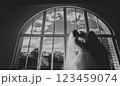 Bride and groom kissing against a semicircular window 123459074