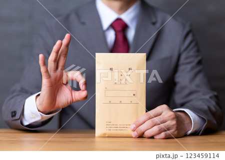 グレーのスーツを着て給料袋を持って丸サインをするミドル男性ビジネスマン 123459114