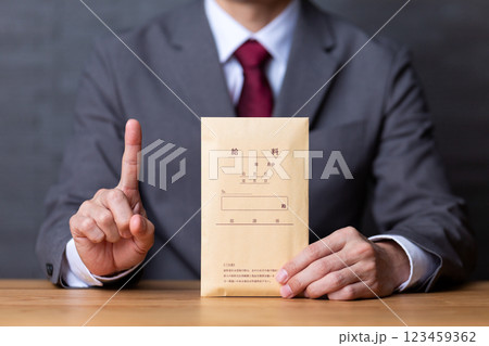 グレーのスーツを着て給料袋を持って人差し指を立てるミドル男性ビジネスマン 123459362