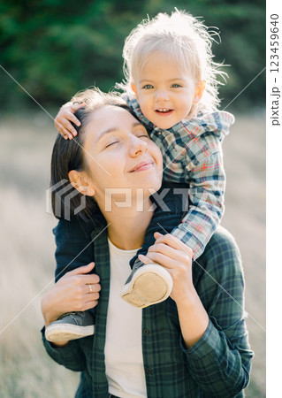 Happy little girl hugging her mom head while sitting on her shoulders. Portrait Happy little girl hugging her mom head while sitting on her shoulders. Portrait 123459640