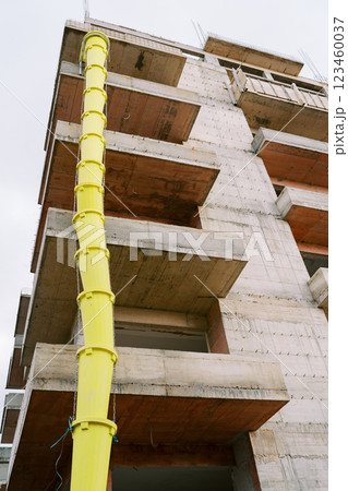 Long yellow pipe stretches up along the balconies of an apartment building under construction 123460037