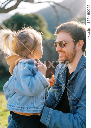 Smiling dad sits on against a little girl with a carrot in her hand Smiling dad sits on against a little girl with a carrot in her hand 123460093