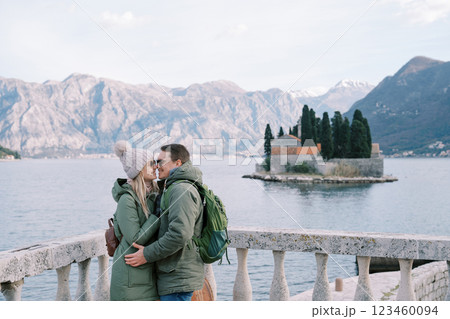 Guy and girl hugging with their noses touching near the balustrade overlooking the island of St. George. Montenegro Guy and girl hugging with their noses touching near the balustrade overlooking the island of St. George. Montenegro 123460094