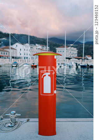 Red fire stand with a fire extinguisher inside stands on a yacht pier 123460152
