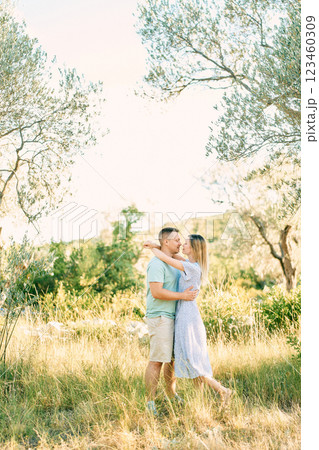 Man hugs and almost kisses woman while standing in a green grove Man hugs and almost kisses woman while standing in a green grove 123460309