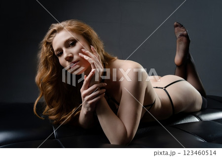 Sensual woman posing in lingerie on a dark leather couch Sensual woman posing in lingerie on a dark leather couch 123460514
