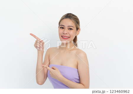 portrait of a Happy Asian woman smiling points her index finger at an empty space in the background and looks straight ahead on white background portrait of a Happy Asian woman smiling points her index finger at an empty space in the background and looks straight ahead on white background 123460962