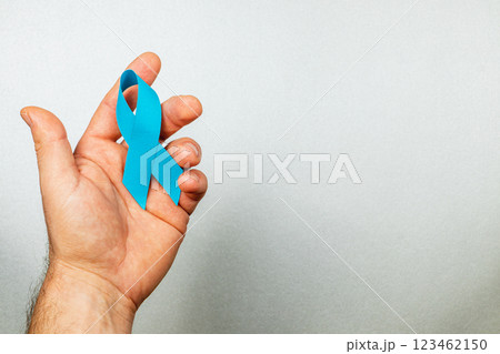 Hand holding a blue awareness ribbon symbolizing cancer support and prevention Hand holding a blue awareness ribbon symbolizing cancer support and prevention 123462150