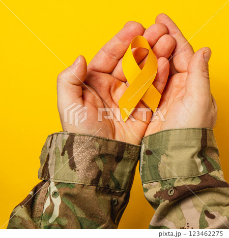 Supporting cancer awareness with a yellow ribbon in hands of a woman 123462275