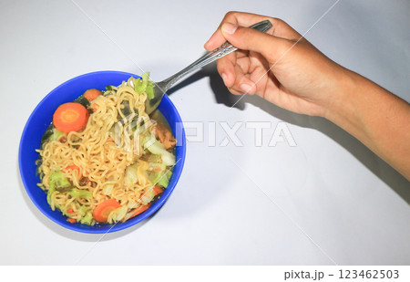 Asian woman's hand holding a spoon picking up noodles in a bowl, healthy food concept Asian woman's hand holding a spoon picking up noodles in a bowl, healthy food concept 123462503